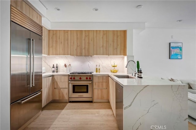399 E Del Mar Blvd Unit 110, Pasadena, CA 91101 - kitchen with high quality appliances, light brown cabinetry, modern cabinets, a peninsula, and light stone counters