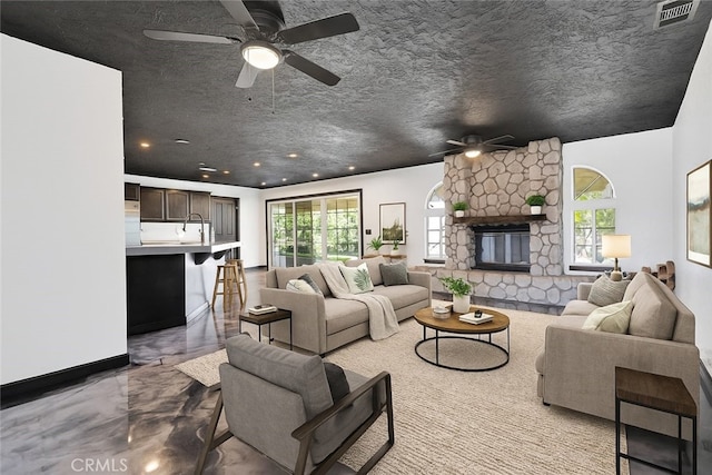 16912 Danbury Ave, Hesperia, CA 92345 - living room with a ceiling fan, healthy amount of natural light, a stone fireplace, recessed lighting, and a textured ceiling