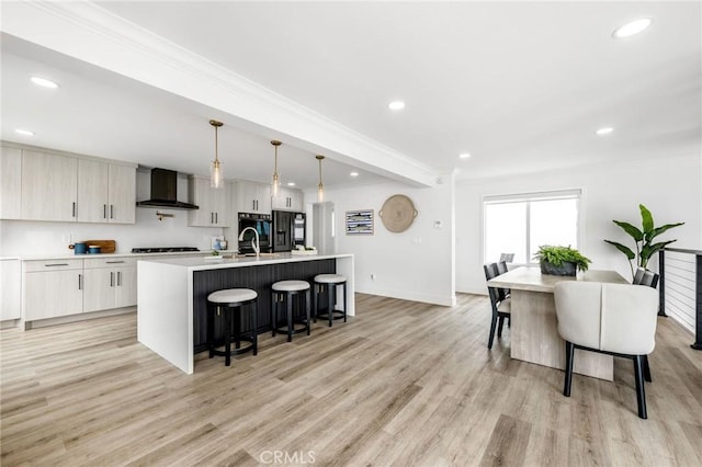 32015 Point Pl, Laguna Beach, CA 92651 - kitchen featuring wall chimney range hood, a breakfast bar area, a kitchen island with sink, light wood-style flooring, and black appliances