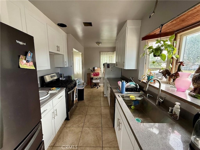 5901 California Ave, Long Beach, CA 90805 - kitchen featuring freestanding refrigerator, stainless steel gas range oven, white cabinets, and light tile patterned floors