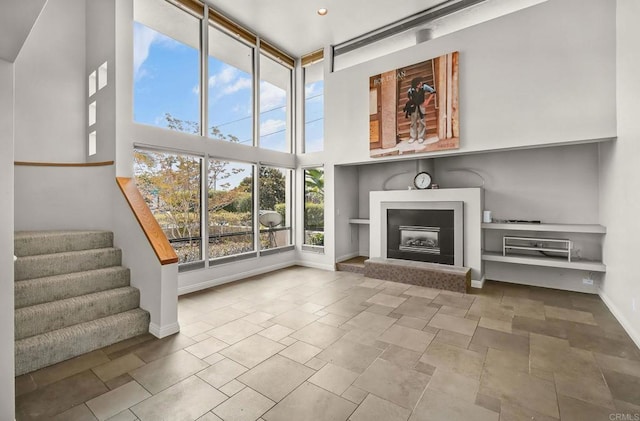 3112 N Mountain View Dr, San Diego, CA 92116 - unfurnished living room featuring a high ceiling, a fireplace with raised hearth, stone finish flooring, and stairs