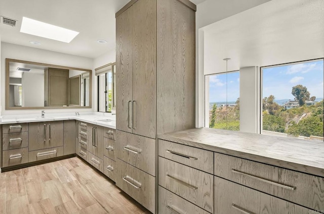 3112 N Mountain View Dr, San Diego, CA 92116 - bathroom featuring a skylight, double vanity, and wood finished floors