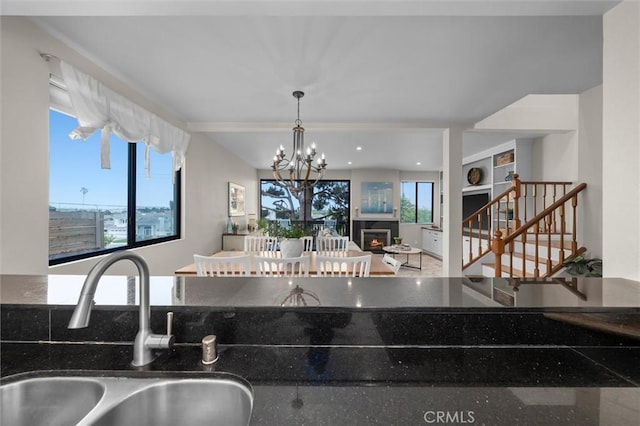 220 S Prospect Ave Unit 9, Redondo Beach, CA 90277 - kitchen with a warm lit fireplace, a chandelier, dark stone counters, and pendant lighting