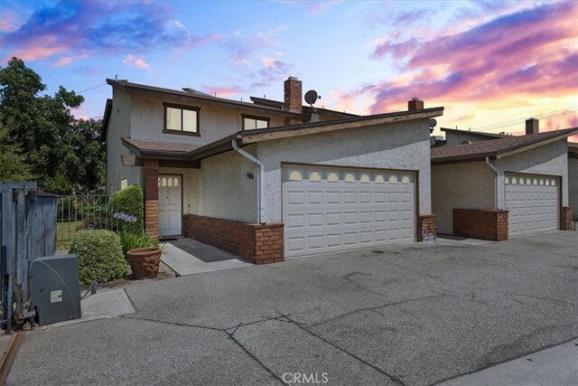 406 Genoa St Unit A, Monrovia, CA 91016 - traditional-style home featuring stucco siding, a garage, brick siding, a chimney, and driveway