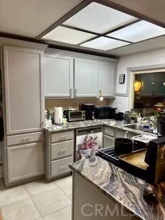13722 Red Hill Ave Unit 20, Tustin, CA 92780 - kitchen with light tile patterned floors, gray cabinetry, and stainless steel dishwasher