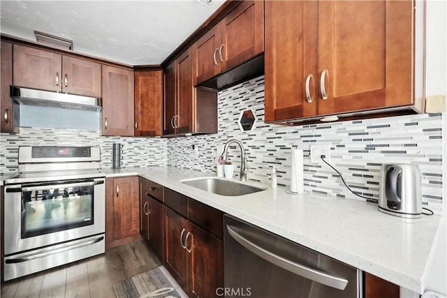 13643 Alcade St, La Puente, CA 91746 - kitchen with stainless steel appliances, under cabinet range hood, light stone counters, decorative backsplash, and wood finished floors