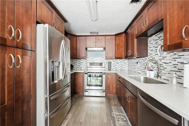 13643 Alcade St, La Puente, CA 91746 - kitchen with appliances with stainless steel finishes, light countertops, light wood-type flooring, decorative backsplash, and under cabinet range hood