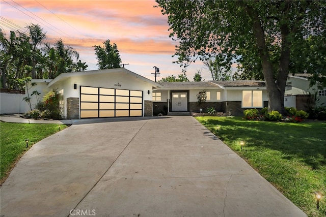 23414 Clarendon St, Woodland Hills, CA 91367 - view of front of house with stucco siding, a front lawn, a garage, concrete driveway, and stone siding