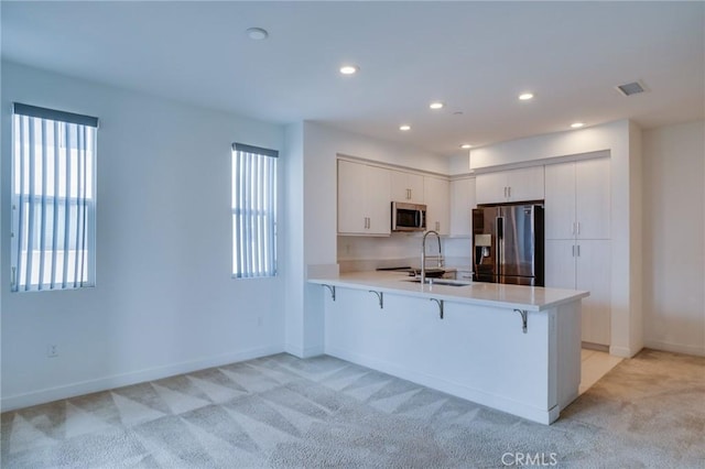 2823 Lily Ln, El Monte, CA 91733 - kitchen featuring stainless steel appliances, a peninsula, light carpet, light countertops, and a breakfast bar area
