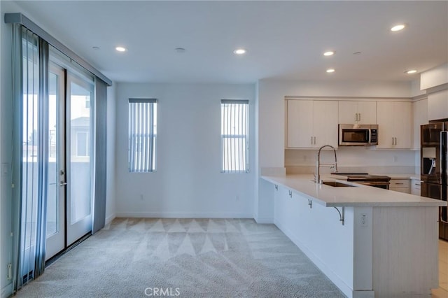 2823 Lily Ln, El Monte, CA 91733 - kitchen with stainless steel microwave, a peninsula, black refrigerator with ice dispenser, light countertops, and light colored carpet
