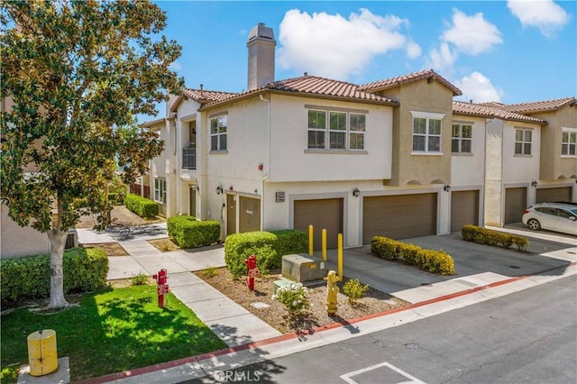 15655 Vista Way Unit 100, Lake Elsinore, CA 92532 - townhome / multi-family property featuring an attached garage, a tiled roof, a chimney, stucco siding, and driveway