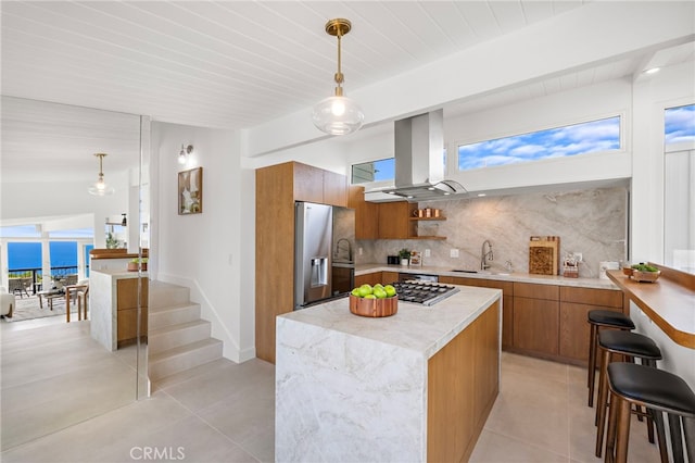 1094 Katella St, Laguna Beach, CA 92651 - kitchen with stainless steel appliances, island exhaust hood, brown cabinets, light tile patterned flooring, and tasteful backsplash