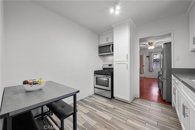 178 E 49th St, Los Angeles, CA 90011 - kitchen with appliances with stainless steel finishes, white cabinetry, ceiling fan, and light wood finished floors