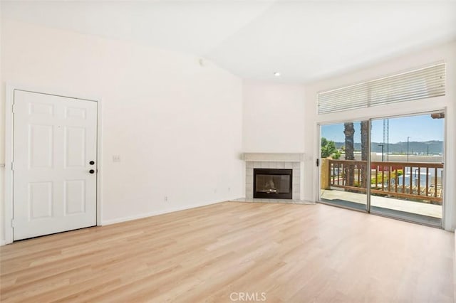 42140 Lyndie Ln Unit 12, Temecula, CA 92591 - unfurnished living room featuring light wood-style floors, a tiled fireplace, and lofted ceiling