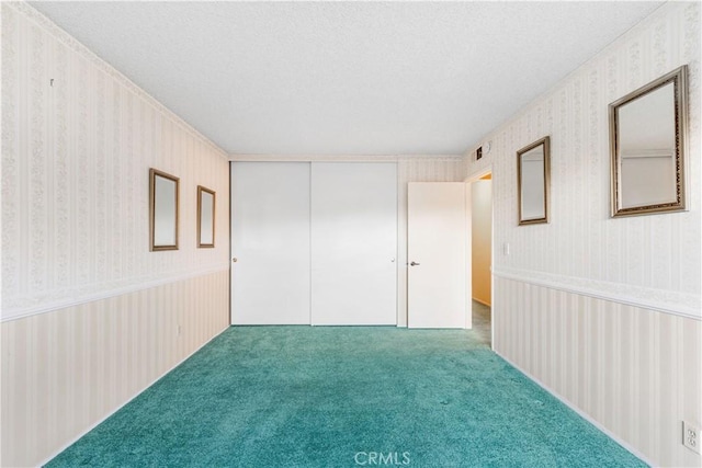 6991 Caminito Perico, San Diego, CA 92119 - unfurnished bedroom with wallpapered walls, a textured ceiling, carpet, and a closet