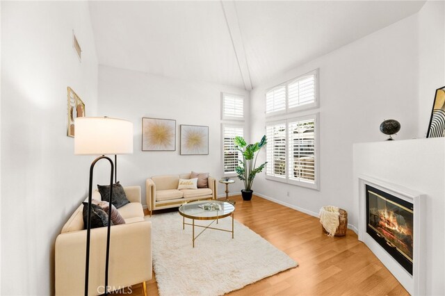 1026 N Turner Ave Unit 223, Ontario, CA 91764 - living room with wood finished floors, a glass covered fireplace, high vaulted ceiling, and beamed ceiling