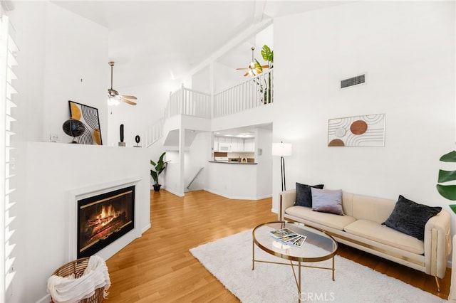 1026 N Turner Ave Unit 223, Ontario, CA 91764 - living room with a ceiling fan, a high ceiling, light wood-style floors, and a glass covered fireplace