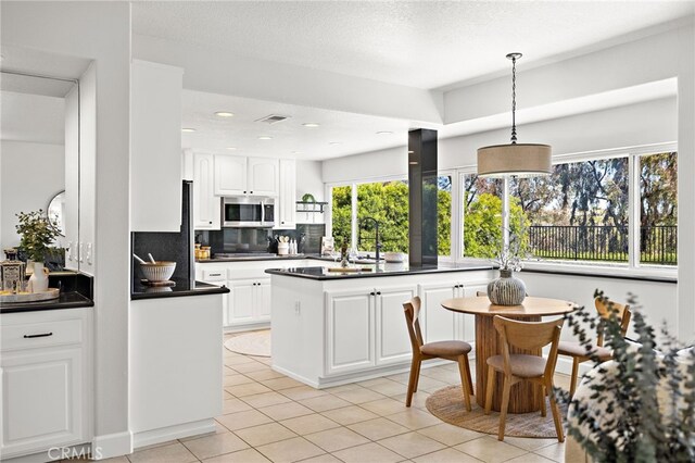 10 Novilla, Laguna Niguel, CA 92677 - kitchen with stainless steel appliances, dark countertops, white cabinetry, light tile patterned floors, and hanging light fixtures