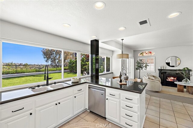 10 Novilla, Laguna Niguel, CA 92677 - kitchen with stainless steel dishwasher, light tile patterned floors, dark countertops, a lit fireplace, and white cabinets