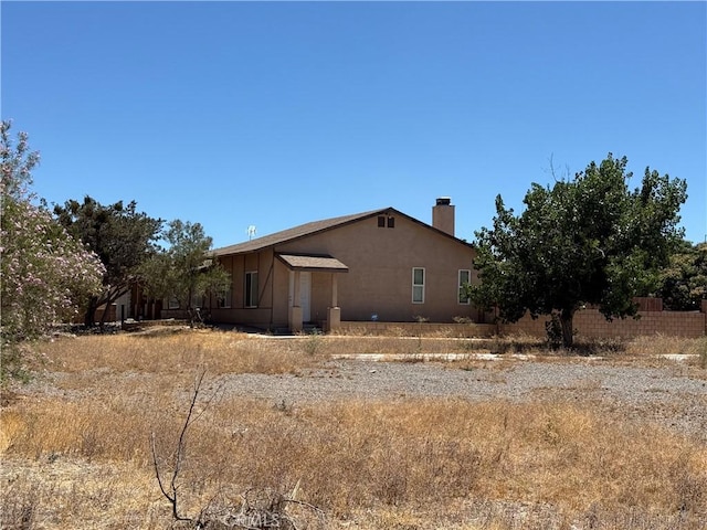 7236 Coyote Trl, Oak Hills, CA 92344 - view of property exterior with a chimney and stucco siding
