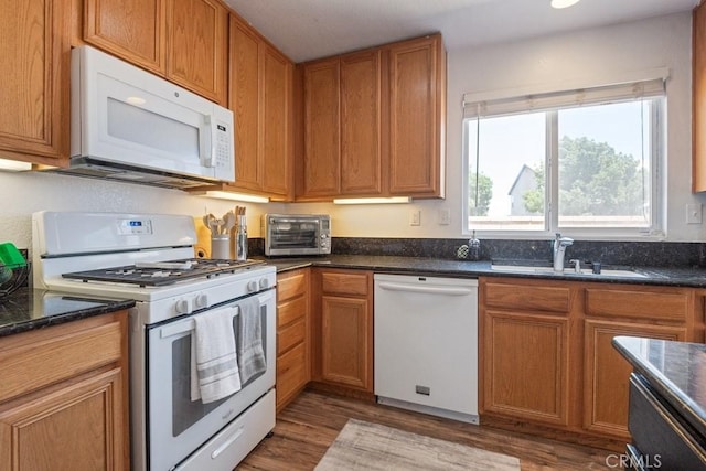 14075 Tourmaline St, Hesperia, CA 92344 - kitchen with white appliances, wood finished floors, dark stone counters, and brown cabinetry