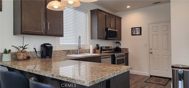 315 Fuente Dr, Guadalupe, CA 93434 - kitchen featuring appliances with stainless steel finishes, dark brown cabinets, dark wood-style floors, recessed lighting, and a peninsula