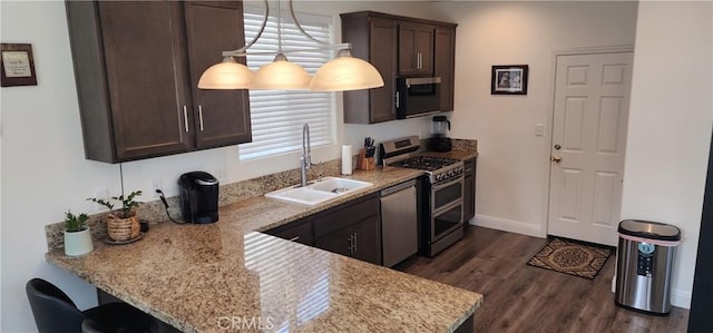 315 Fuente Dr, Guadalupe, CA 93434 - kitchen with stainless steel appliances, dark brown cabinetry, dark wood-style floors, a peninsula, and light stone counters