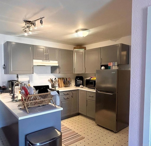 3029 Broadway Unit 22, San Diego, CA 92102 - kitchen with freestanding refrigerator, under cabinet range hood, gray cabinetry, stainless steel microwave, and light countertops