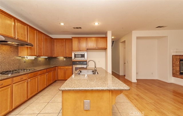 26508 Veramonte Ave, Murrieta, CA 92562 - kitchen featuring stainless steel appliances, under cabinet range hood, recessed lighting, brown cabinetry, and decorative backsplash