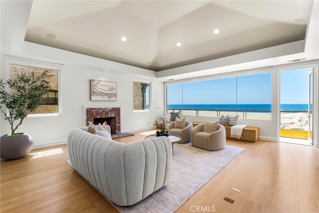 1554 E Oceanfront, Newport Beach, CA 92661 - living room with light wood finished floors, plenty of natural light, a brick fireplace, a water view, and vaulted ceiling