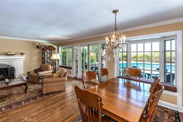 5591 Kenwood Ave, Buena Park, CA 90621 - dining space with wood finished floors, ornamental molding, a chandelier, and a brick fireplace