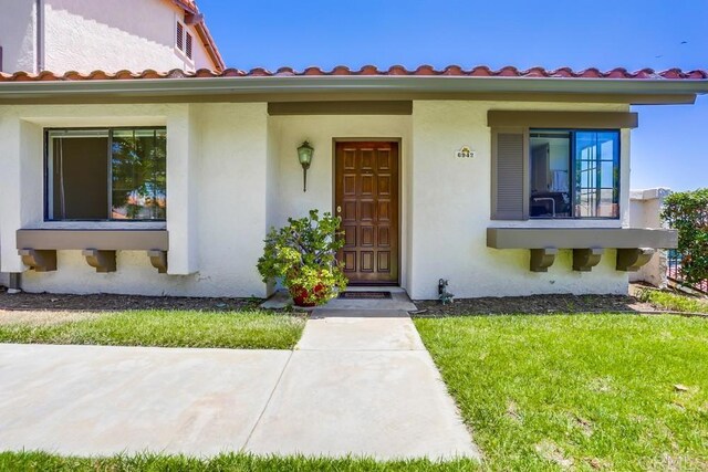 6942 Batiquitos, Carlsbad, CA 92011 - view of front facade featuring stucco siding, a tile roof, and a front lawn