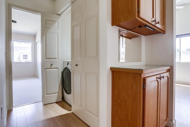6942 Batiquitos, Carlsbad, CA 92011 - laundry area with light wood-type flooring, washer / clothes dryer, and cabinet space