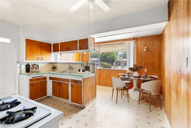 1450 Pepper Tree Ln, San Bernardino, CA 92404 - kitchen with light flooring, brown cabinetry, light countertops, wooden walls, and a ceiling fan