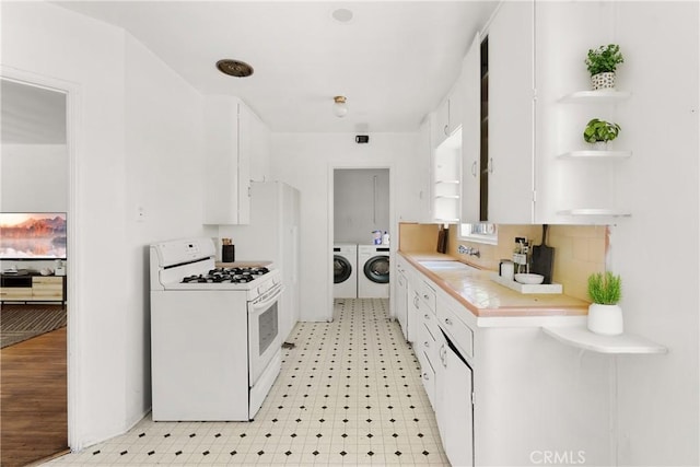 549 E Evans St, San Bernardino, CA 92404 - kitchen featuring white range with gas cooktop, independent washer and dryer, light flooring, light countertops, and white cabinets