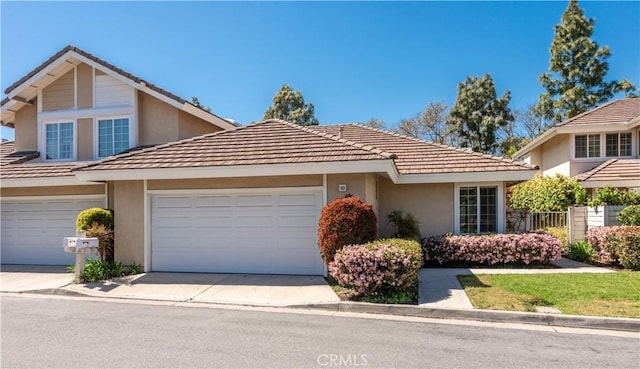 10 Windsong, Irvine, CA 92614 - view of front of house with stucco siding, a tiled roof, driveway, and a garage