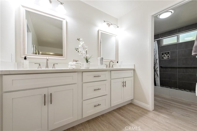 10 Windsong, Irvine, CA 92614 - bathroom featuring double vanity, tiled shower, and wood finished floors