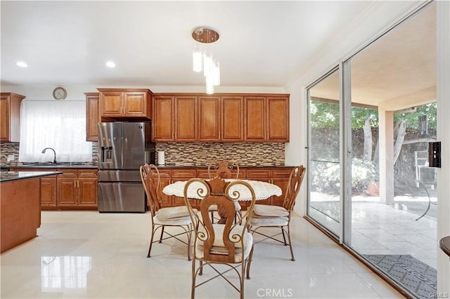 22329 Plummer St, Chatsworth, CA 91311 - kitchen featuring stainless steel fridge with ice dispenser, dark countertops, backsplash, brown cabinetry, and hanging light fixtures