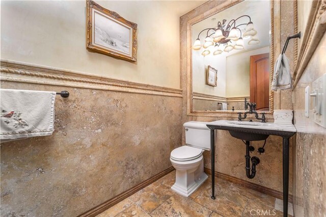 919 S Gretna Green Way, Los Angeles, CA 90049 - half bath featuring wainscoting and stone finish floors