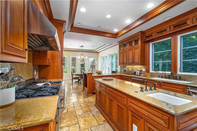 919 S Gretna Green Way, Los Angeles, CA 90049 - kitchen with stainless steel appliances, wall chimney exhaust hood, stone tile flooring, ornamental molding, and tasteful backsplash