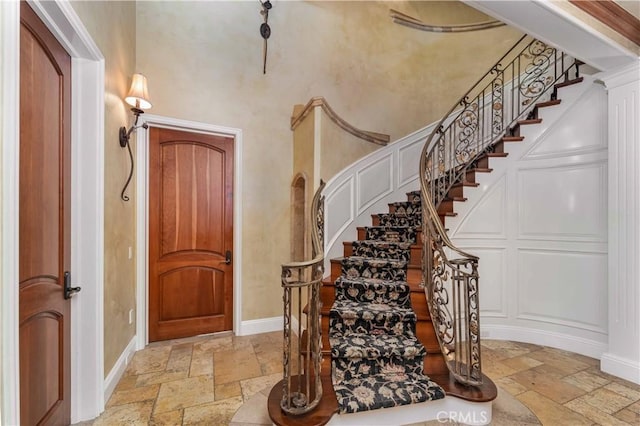 919 S Gretna Green Way, Los Angeles, CA 90049 - foyer entrance featuring stone tile floors, stairs, a decorative wall, and a towering ceiling