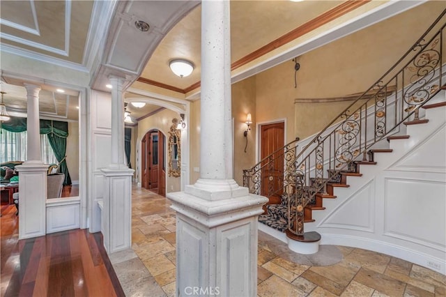 919 S Gretna Green Way, Los Angeles, CA 90049 - foyer with decorative columns, ornamental molding, arched walkways, stone tile flooring, and a decorative wall