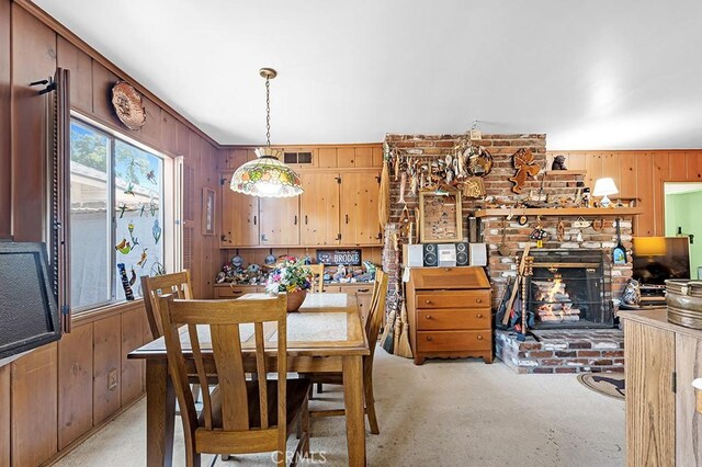 15043 Tuba St, San Fernando, CA 91345 - dining space featuring wood walls, light carpet, and a brick fireplace