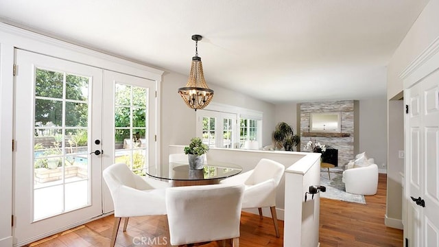 23782 Lagarto, Mission Viejo, CA 92691 - dining space with french doors, a chandelier, a large fireplace, and light wood-type flooring