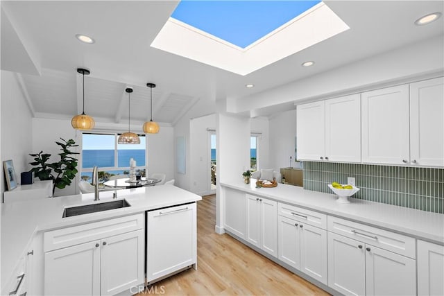 21659 Ocean Vista Dr Unit 20, Laguna Beach, CA 92651 - kitchen featuring dishwashing machine, a skylight, a peninsula, light wood finished floors, and white cabinets