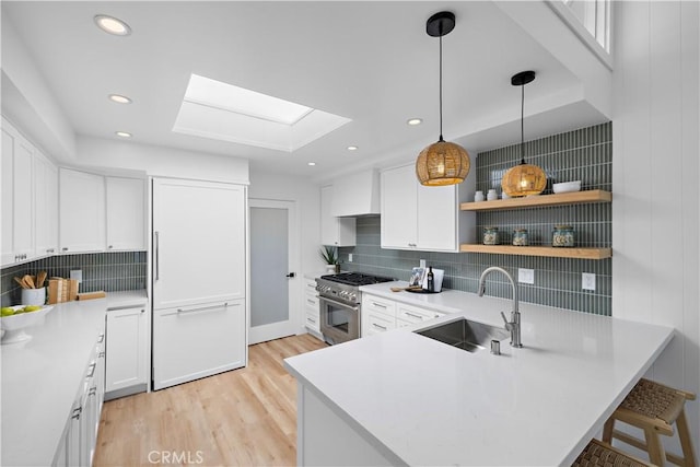 21659 Ocean Vista Dr Unit 20, Laguna Beach, CA 92651 - kitchen featuring high end stove, light wood-style flooring, a peninsula, a skylight, and tasteful backsplash