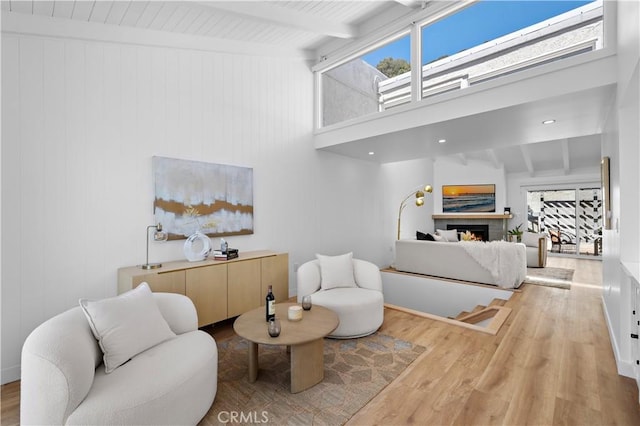 21659 Ocean Vista Dr Unit 20, Laguna Beach, CA 92651 - living area featuring healthy amount of natural light, a warm lit fireplace, beam ceiling, wood finished floors, and a towering ceiling