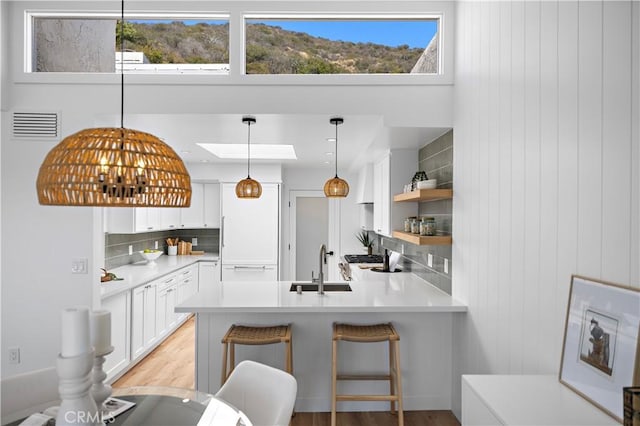 21659 Ocean Vista Dr Unit 20, Laguna Beach, CA 92651 - kitchen featuring a peninsula, backsplash, white cabinetry, light countertops, and hanging light fixtures
