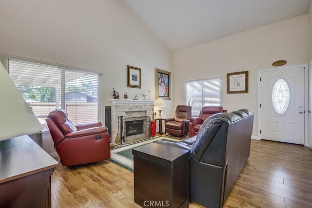 13418 Palm Pl, Cerritos, CA 90703 - living area with healthy amount of natural light, high vaulted ceiling, light wood-style flooring, and a stone fireplace