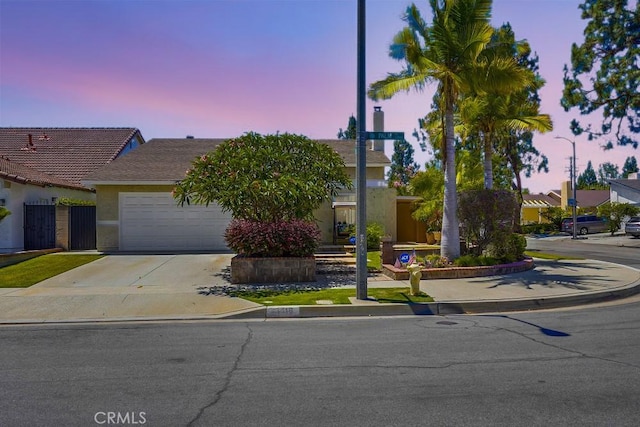 13418 Palm Pl, Cerritos, CA 90703 - view of property hidden behind natural elements featuring a garage, concrete driveway, and stucco siding